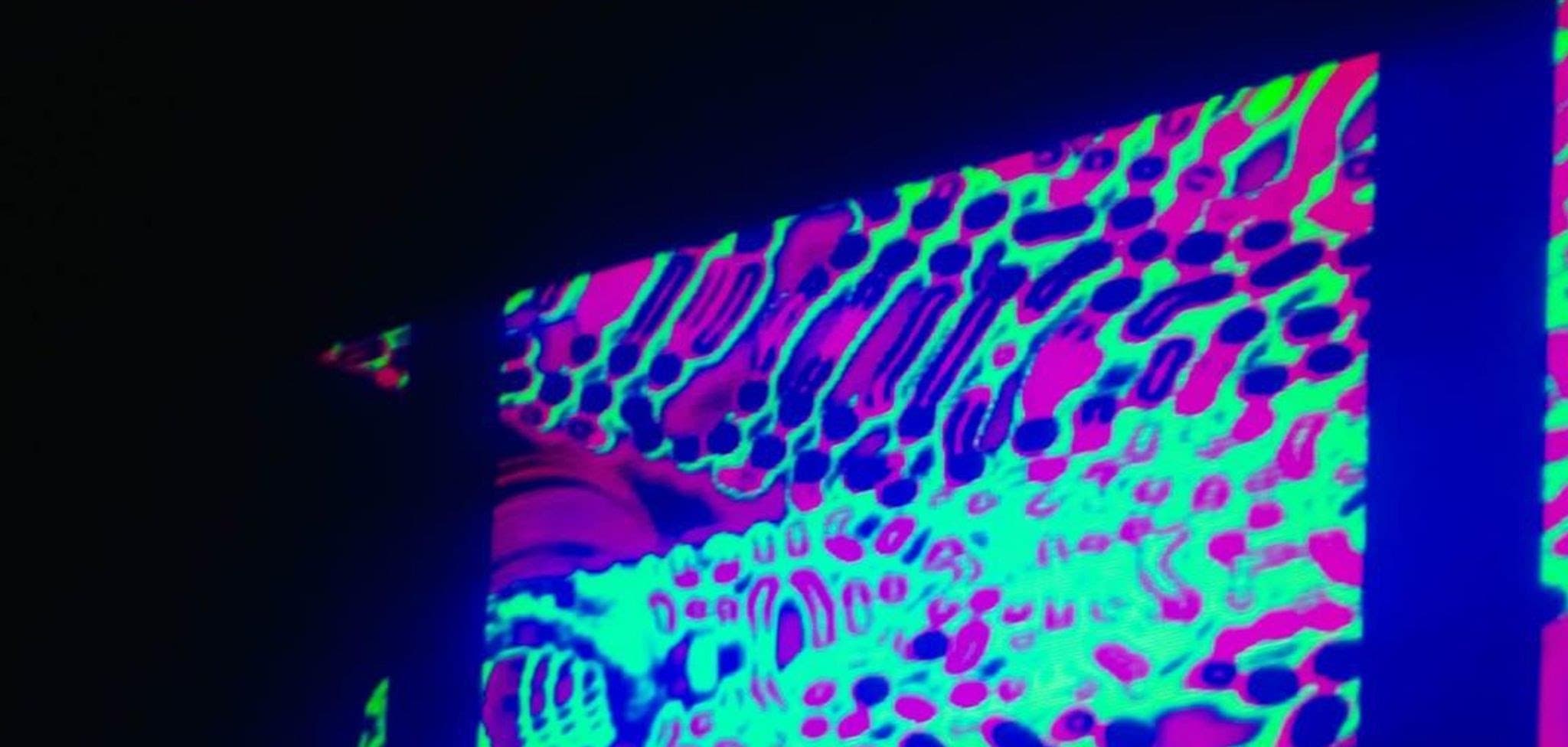 A projection of green and magenta patterns across a dark wall at Method Delhi.